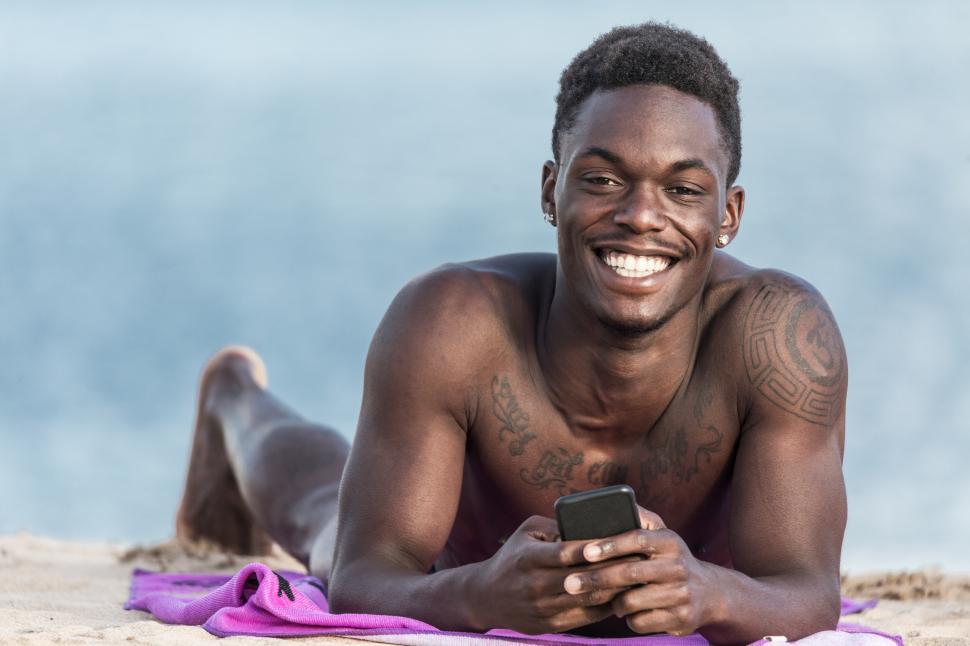 Free Image of Cheerful man with smartphone on beach 