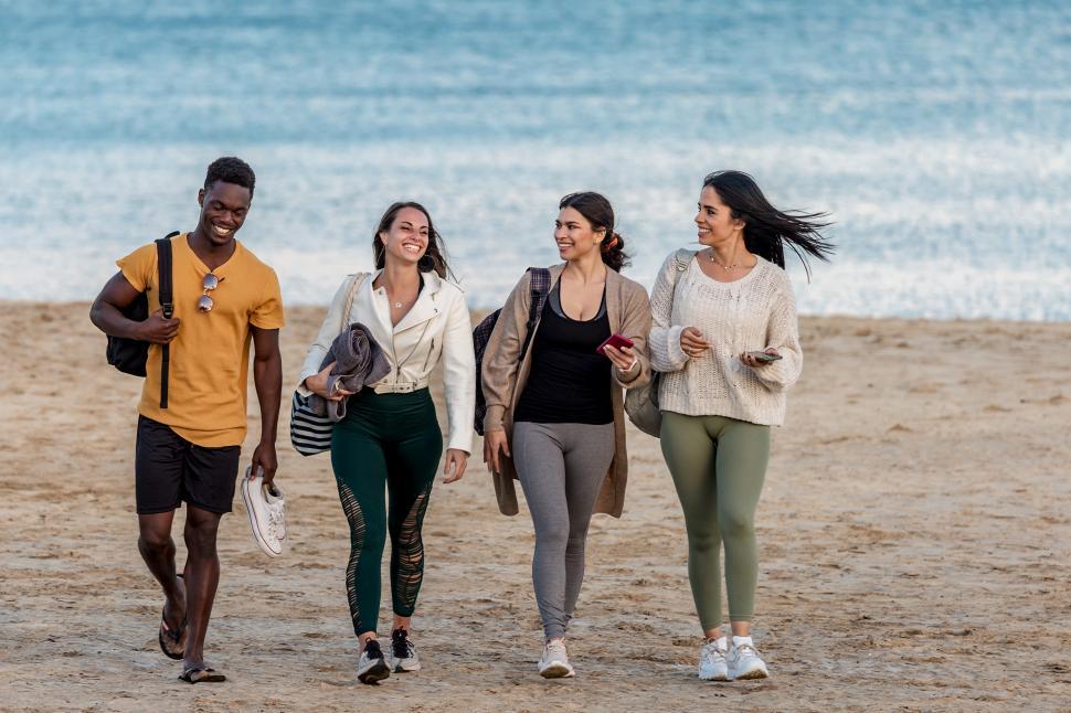 Free Image of Cheerful diverse friends walking on beach together 