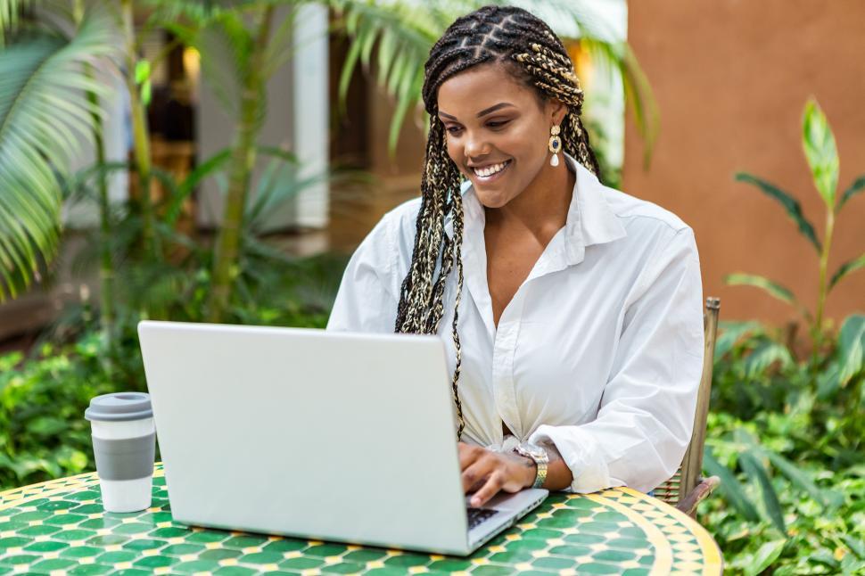 Free Image of African American woman using laptop in a cafe store outside 