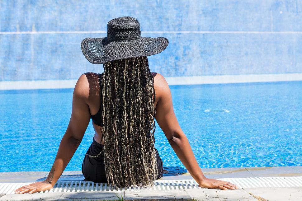 Download Free Stock Photo of Rear view of an African-American woman sitting on the edge of a pool 