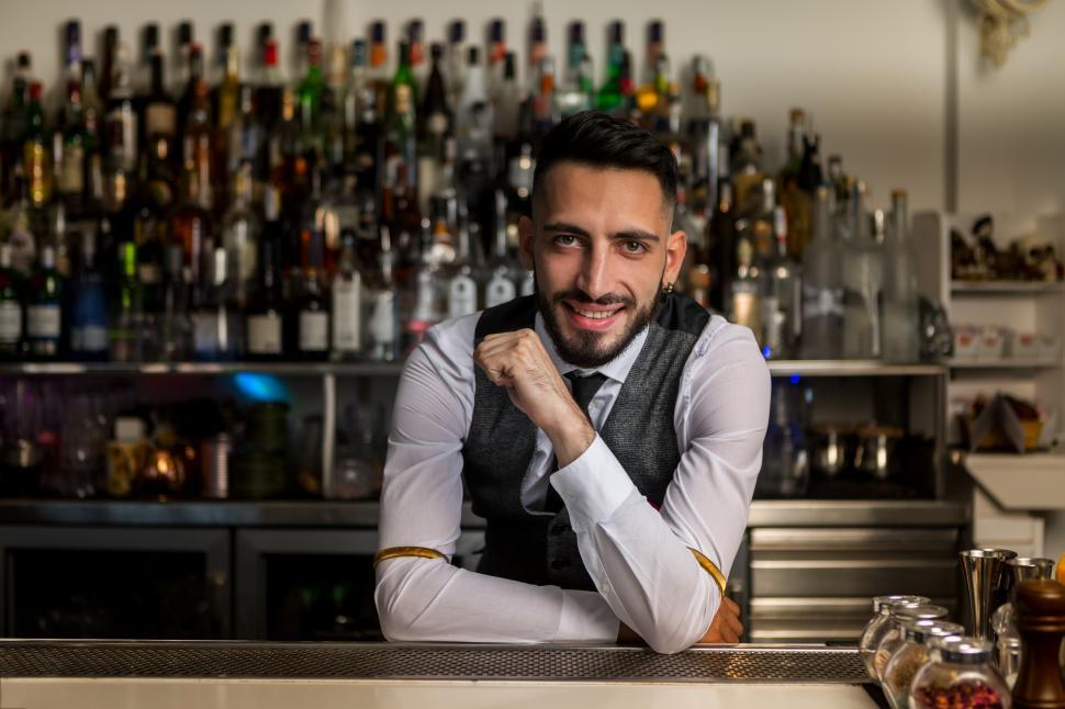 Download Free Stock Photo of Smiling barman standing at bar counter 