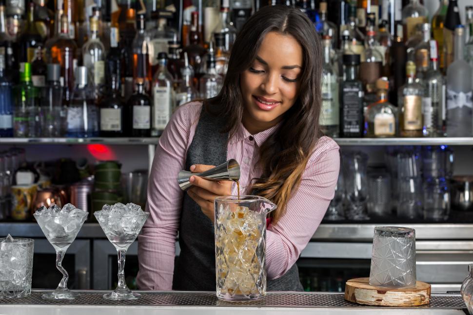 Download Free Stock Photo of Positive female barkeeper making cocktail in bar 