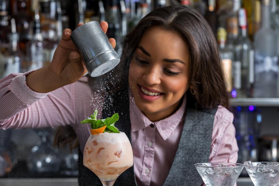 Download Free Stock Photo of Happy female barkeeper adding powdered sugar to cocktail 