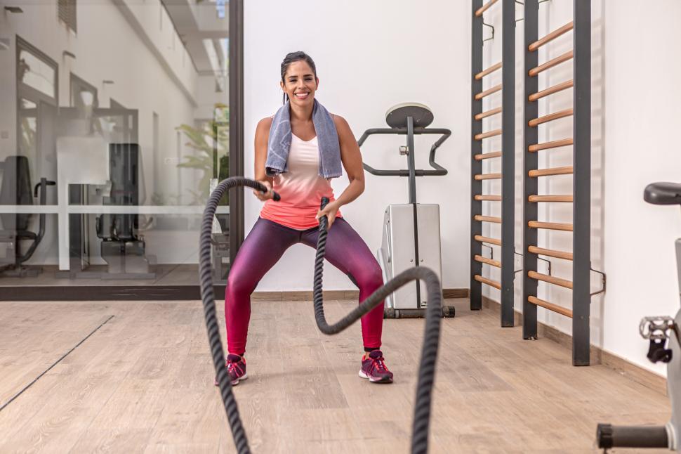 Free Image of Young adult woman in sportswear exercising with battle ropes 