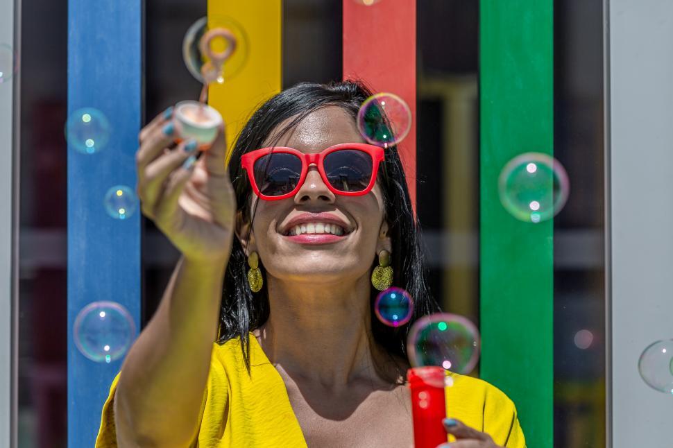 Free Image of Latina adult woman smiling and holding bubbles wand 