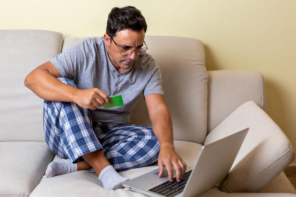 Download Free Stock Photo of Young Caucasian male sitting on a couch using a laptop computer 