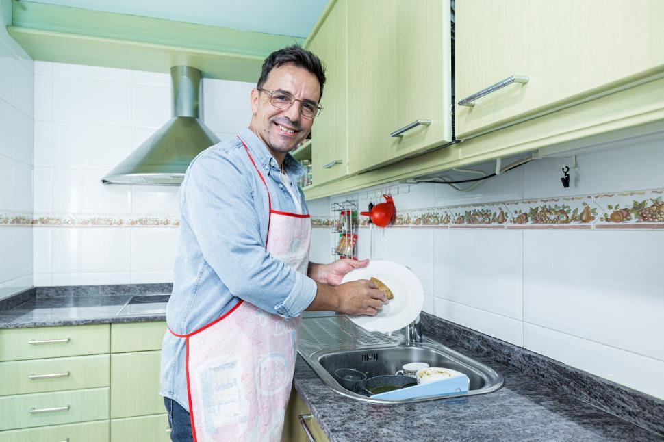 Free Image of Adult male washing dishes in the kitchen at home 
