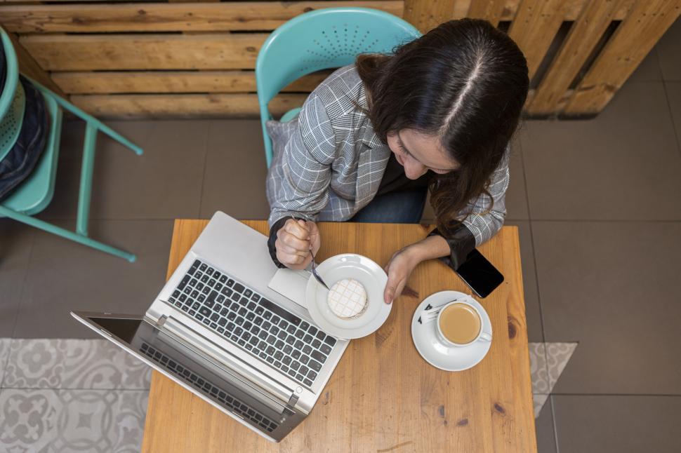 Free Image of Woman eating dessert and drinking coffee during online work 