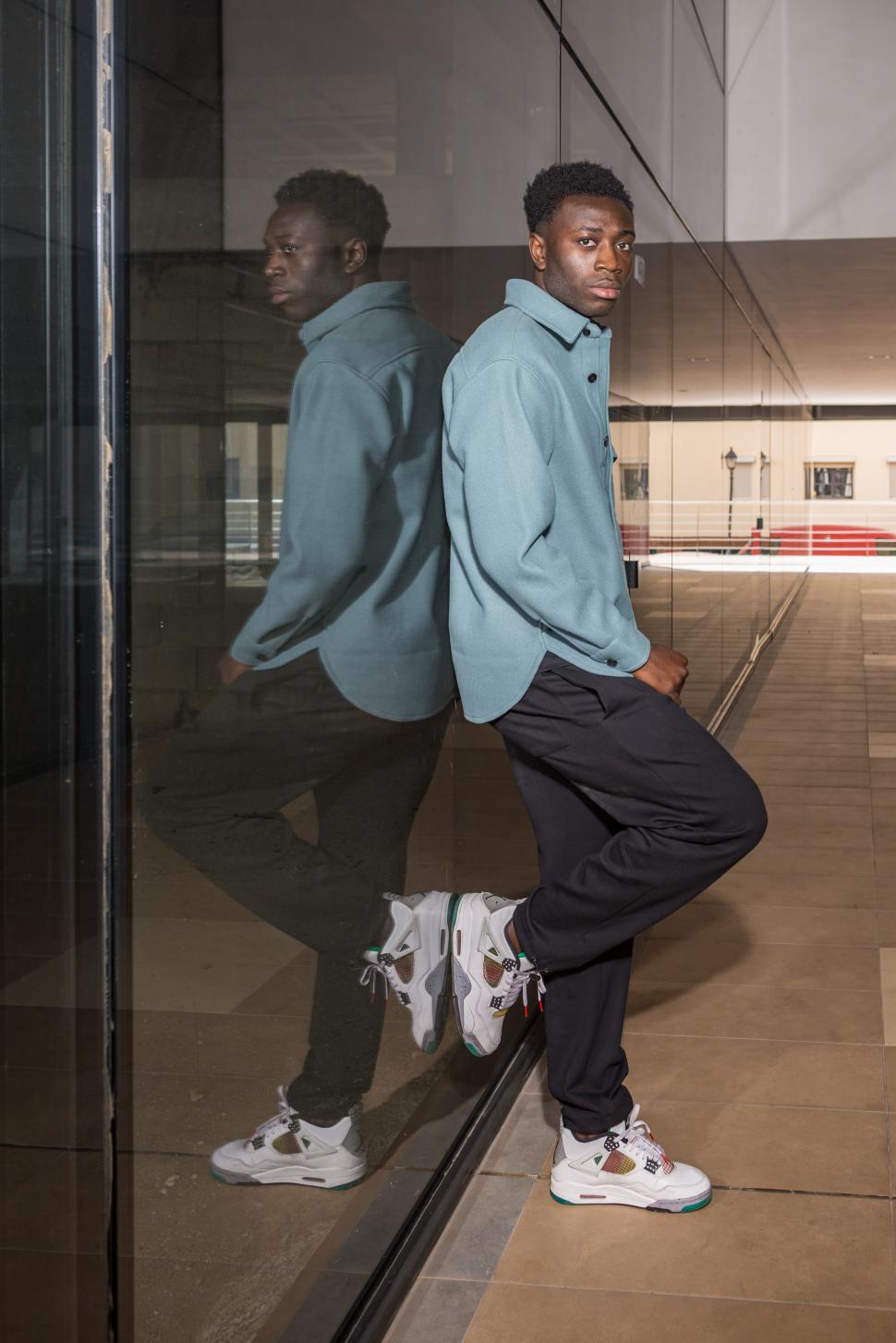 Download Free Stock Photo of Fashionable young African American guy leaning on glass wall 