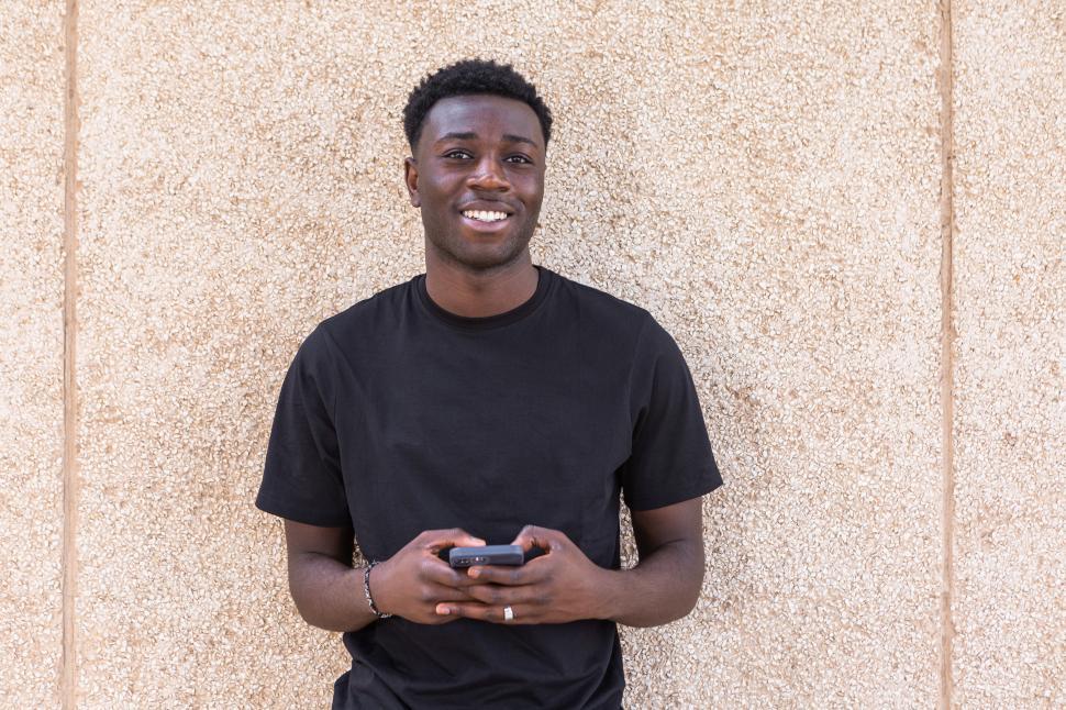Free Image of Positive black man using smartphone and smiling at camera 