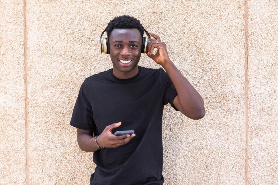 Free Image of Joyful young ethnic man smiling while listening to music in headphones 