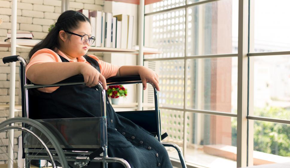 Free Image of Girl sitting in a wheelchair looking at the window 