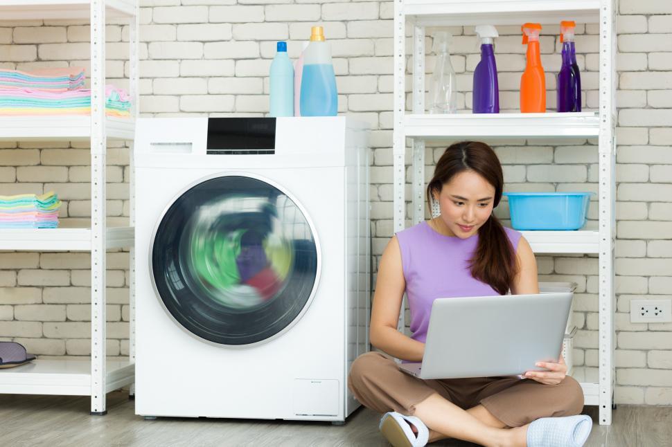 Free Image of Working on a laptop while doing laundry 
