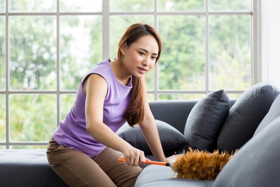 Free Image of Woman is dusting the sofa. 