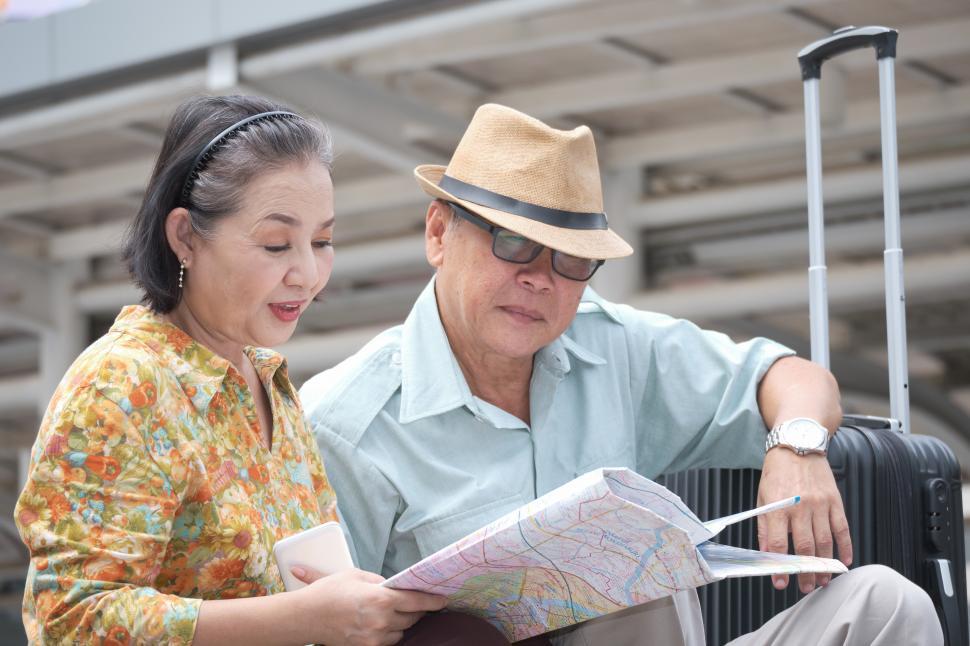 Free Image of Senior couple are sitting holding the map to search for destination 