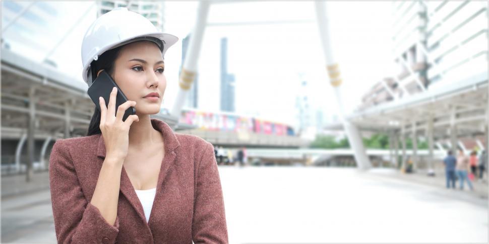 Free Image of Confident working woman is wearing helmet and using cellphone 