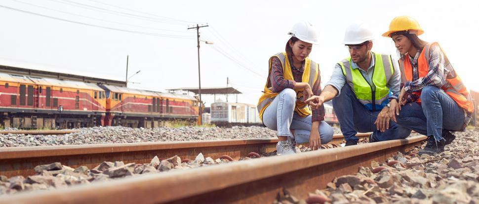 Free Image of Rail logistics engineers crouching on train tracks. 