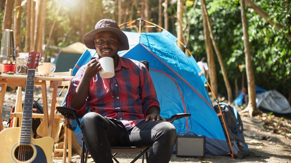 Free Image of A man sitting in front of a camping tent. 