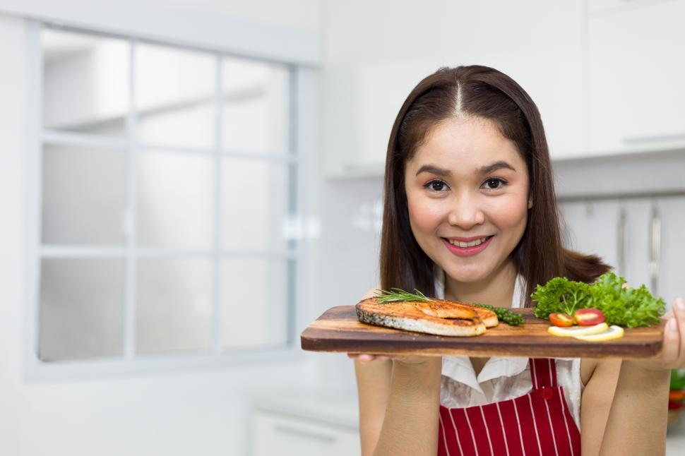 Free Image of Young woman holding a tray of salmon steak. 