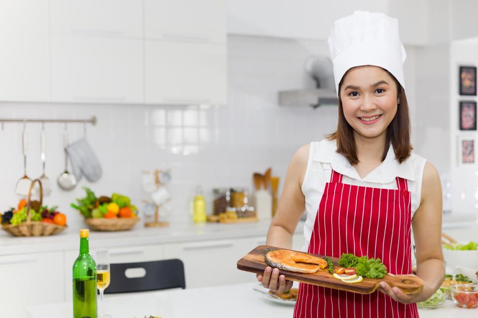 Free Image of Cheerful woman holding plate of steak in kitchen 