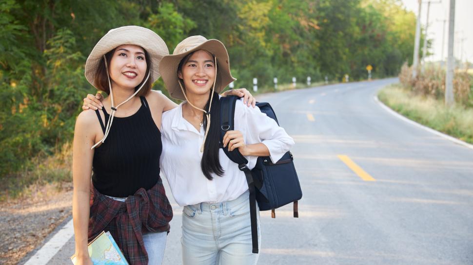Free Image of Two female travelers walking on a country road together 