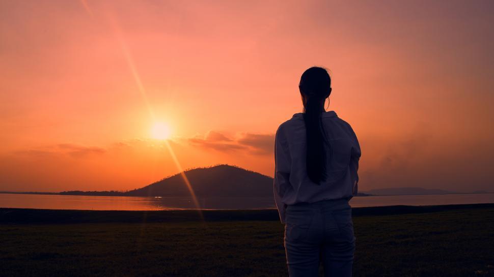 Free Image of Woman standing watching the sunset. 