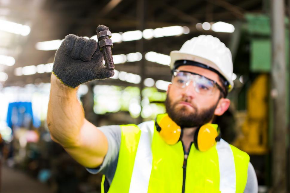 Free Image of Factory worker holding a large bolt in the warehouse. 