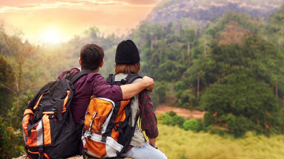 Free Image of Tourist couple watching the sunset on the mountain. 