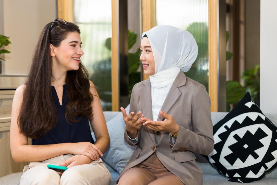 Free Image of A Muslim woman chatting with a caucasian woman on the sofa 