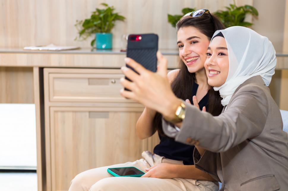 Free Image of Two young businesswomen taking pictures together with their phone 