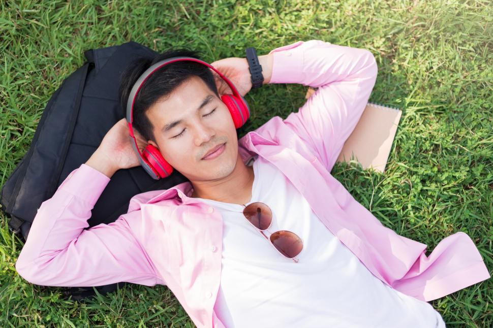 Free Image of Man listening to music with headphones on the grass 