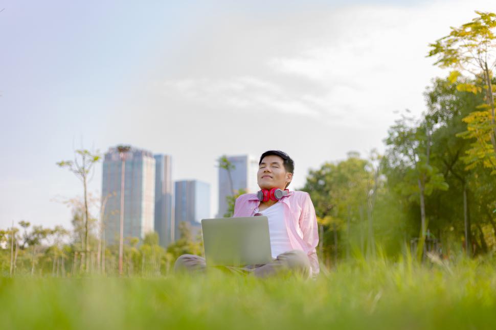 Free Image of Young Asian man is refreshed while relaxing outdoors 