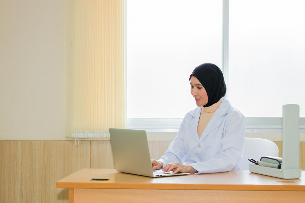 Download Free Stock Photo of Arab female doctor using laptop in examination room. 