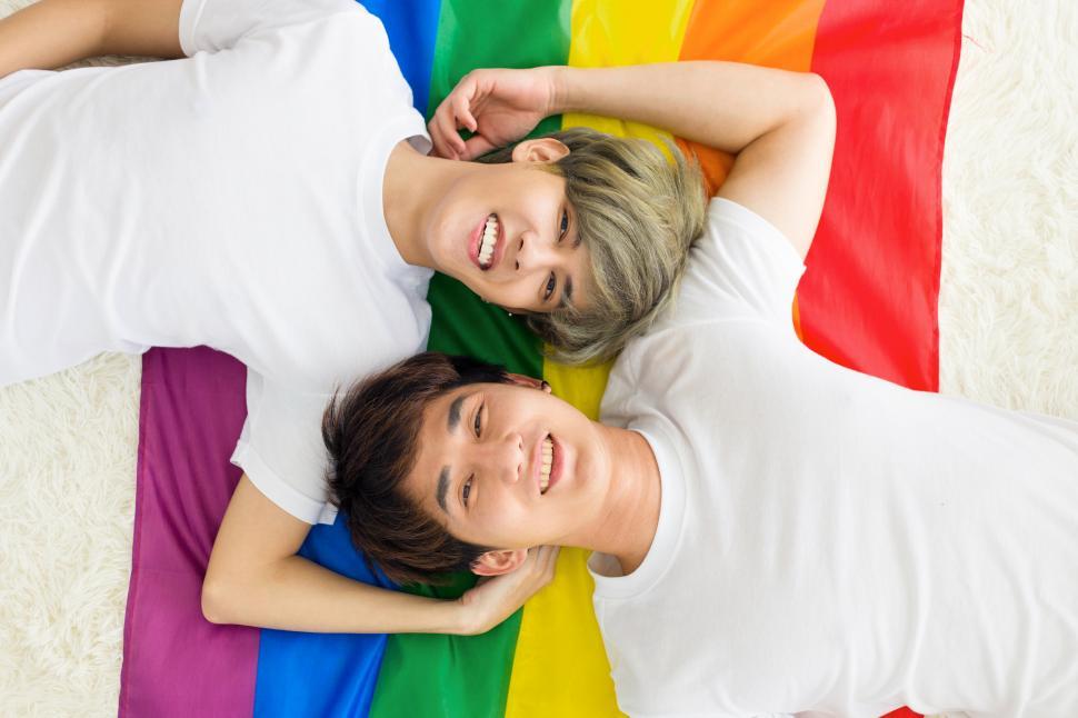 Free Image of Gay couple laying with a rainbow flag. 