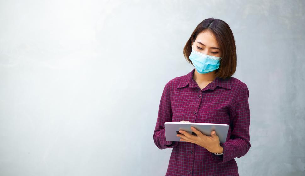 Free Image of A woman wearing an anti-virus mask is using a tablet. 