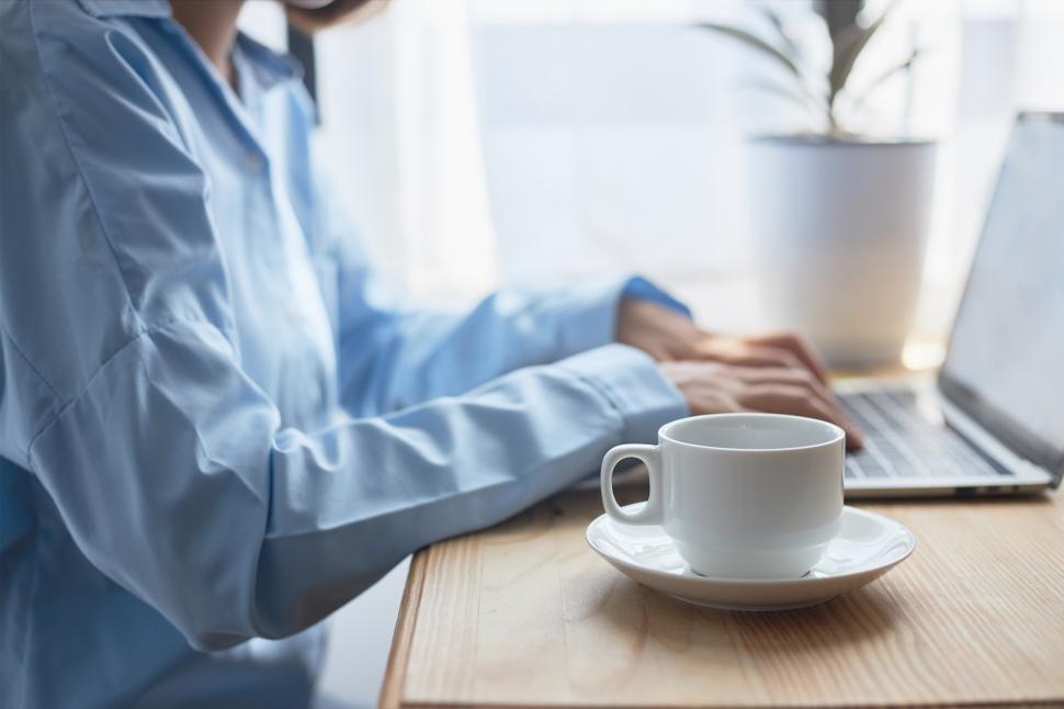 Download Free Stock Photo of A woman working on a laptop with morning coffee at home. 