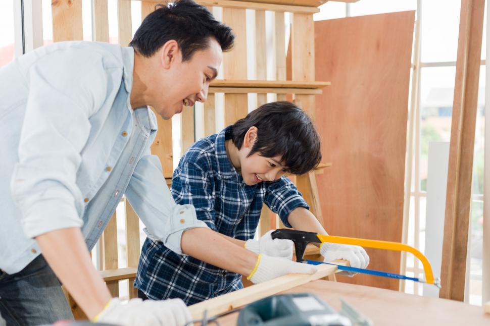 Free Image of Son is sawing wood to help his father around the house 