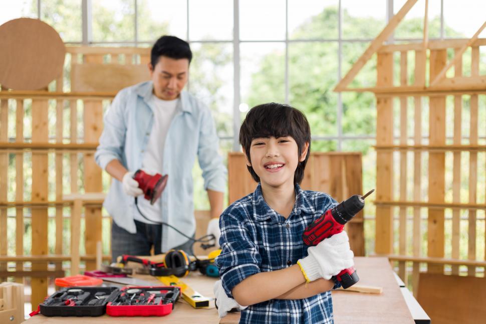 Download Free Stock Photo of A lovely son helps his father do carpentry at home. 