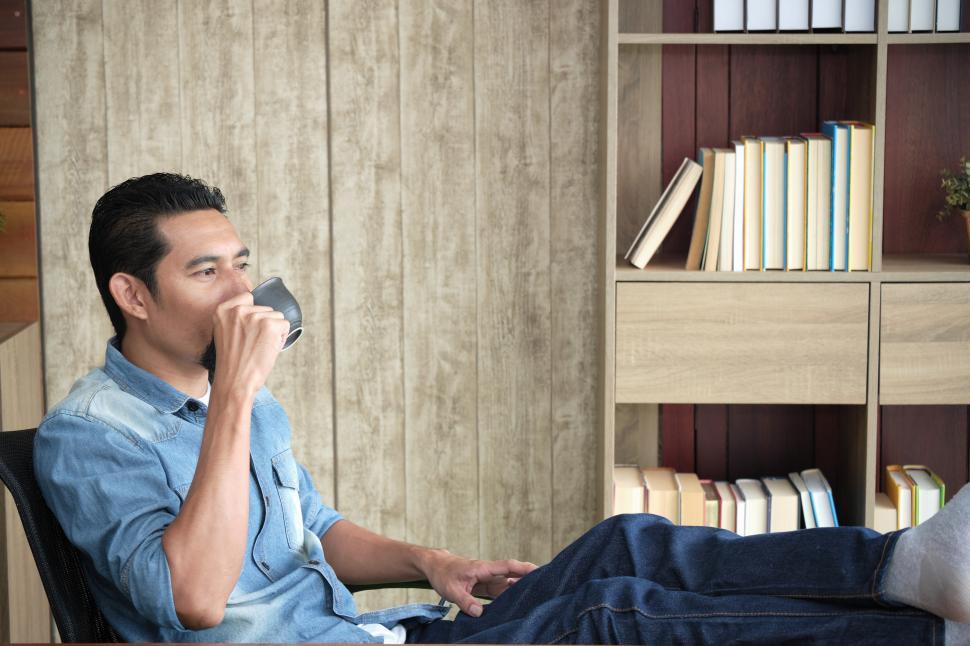Free Image of Guy is drinking coffee in a comfortable mood at his office 