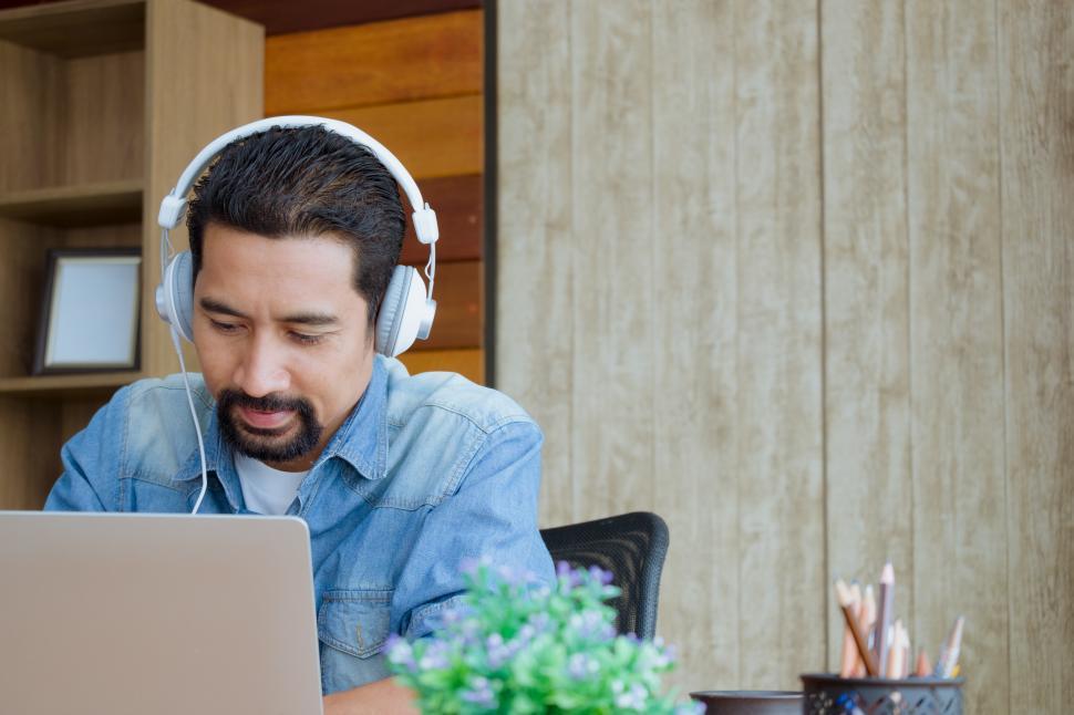 Download Free Stock Photo of Business Owner wearing earphones and using a laptop 