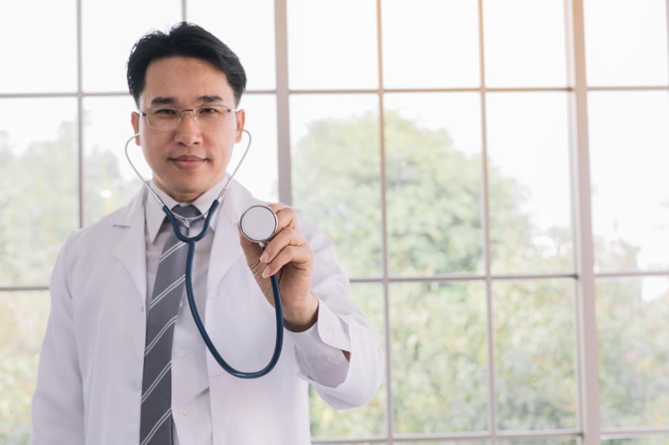 Free Image of Doctor stands holding a headset in his office 