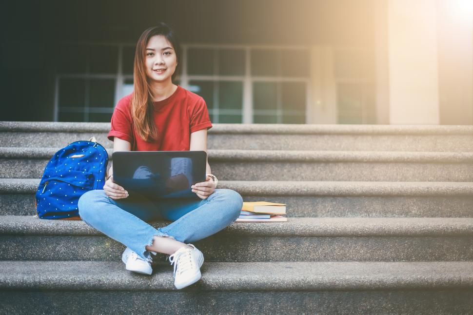 Free Image of Young woman are sitting on steps with a notebook 