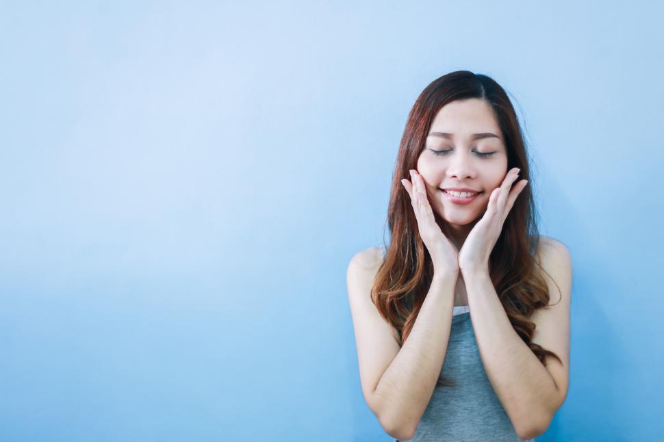Free Image of Young asian woman with beautiful smile and hands touching her face 