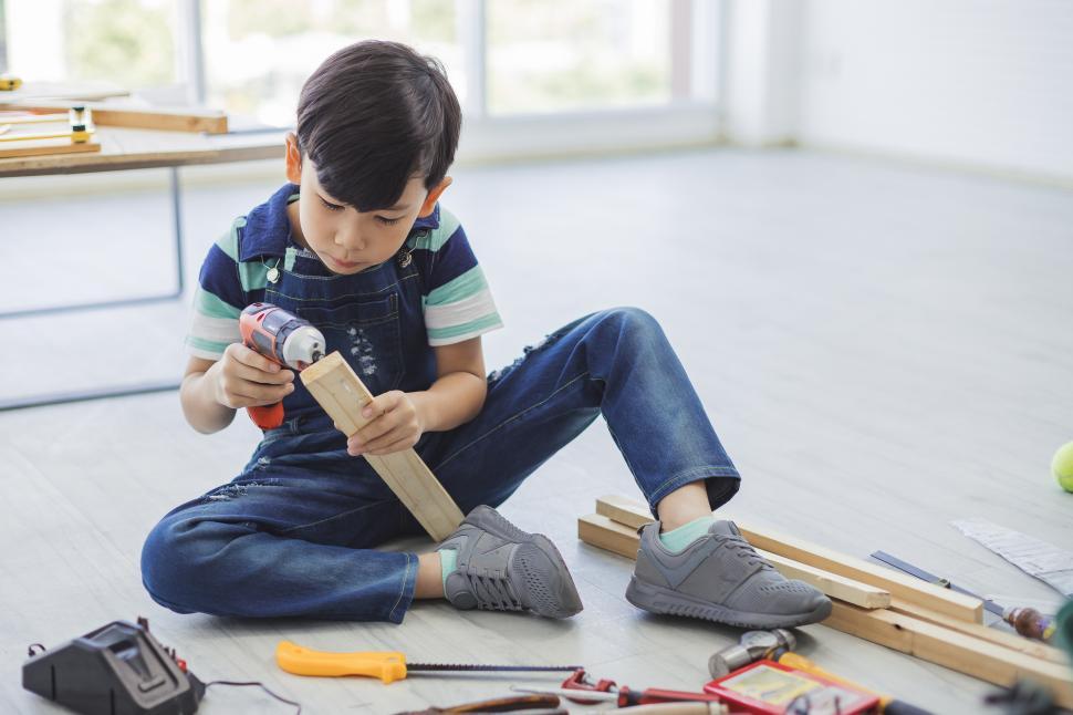 Free Image of Engineering concept - A boy is using a drill driver 