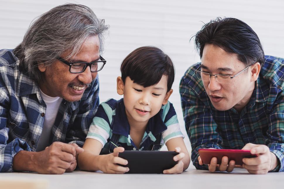 Download Free Stock Photo of Father and grandfather are teaching a little boy to use a smartphone 