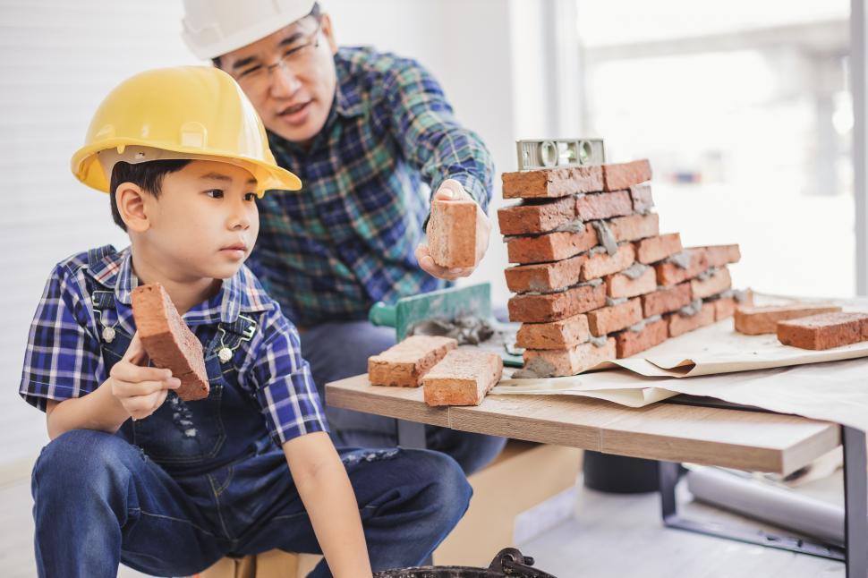 Free Image of Little engineer is helping his father lay the bricks 