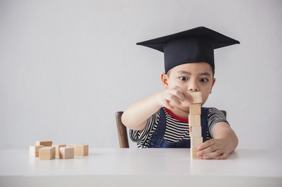 Free Image of Little boy is learning to stack wooden blocks on the table 