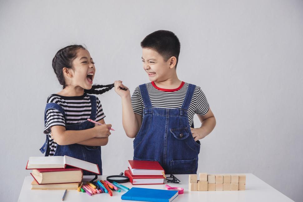 Free Image of Back to school. Little boy and little girl are teasing each other 