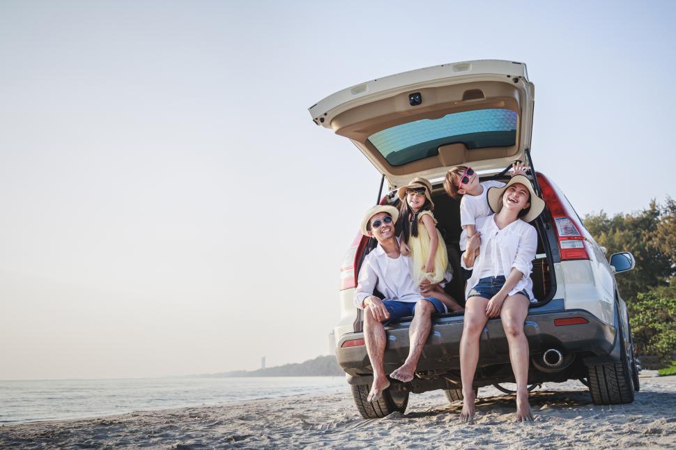 Free Image of Happy family sitting in car hatch. A day at the beach. 