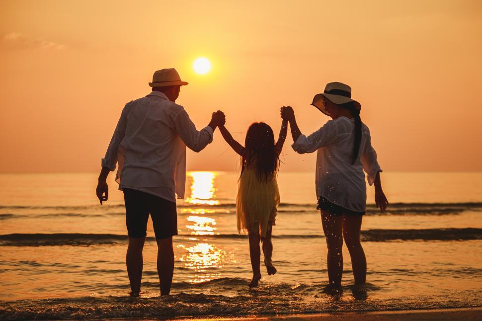 Free Image of Little Girl and happy parents enjoy sunset at the beach 
